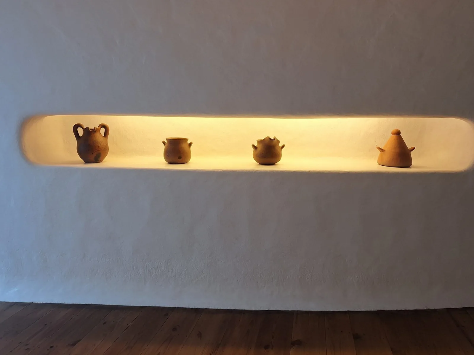 Nicho iluminado com quatro vasos de barro