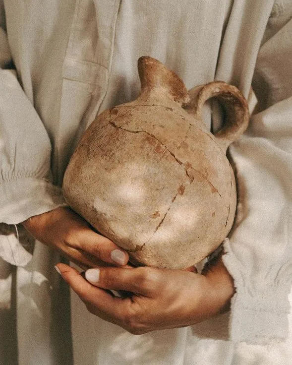 Mãos segurando um vaso de barro