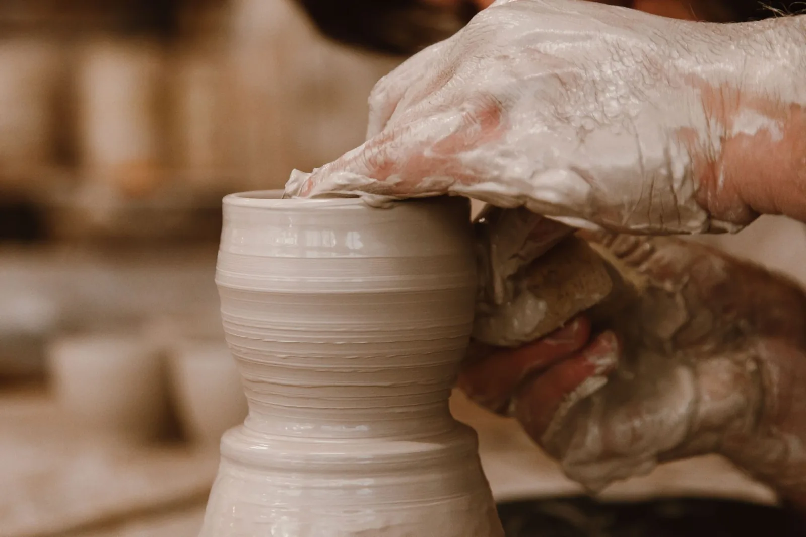 Mãos moldando um vaso no torno